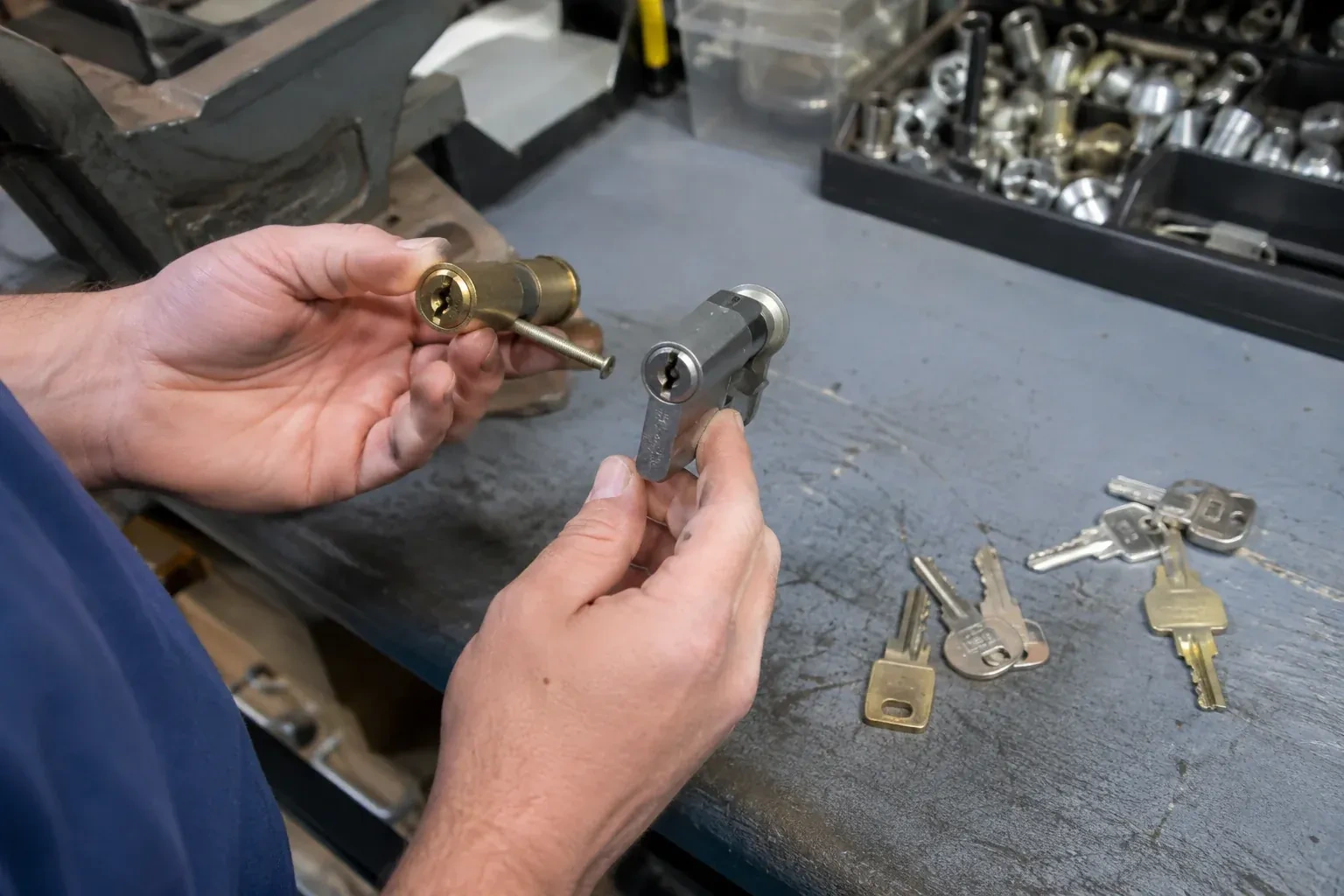 Hands comparing detached lock cylinders beside loose keys on a workbench. — Broken Key Extraction, Collingwood